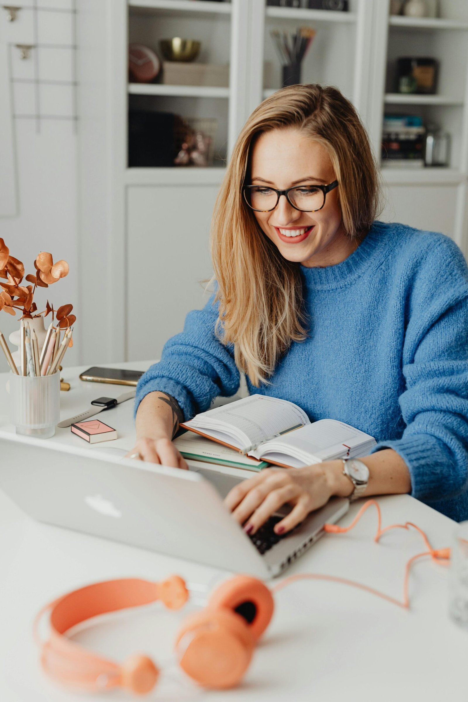 Smiling woman working on laptop with headphones