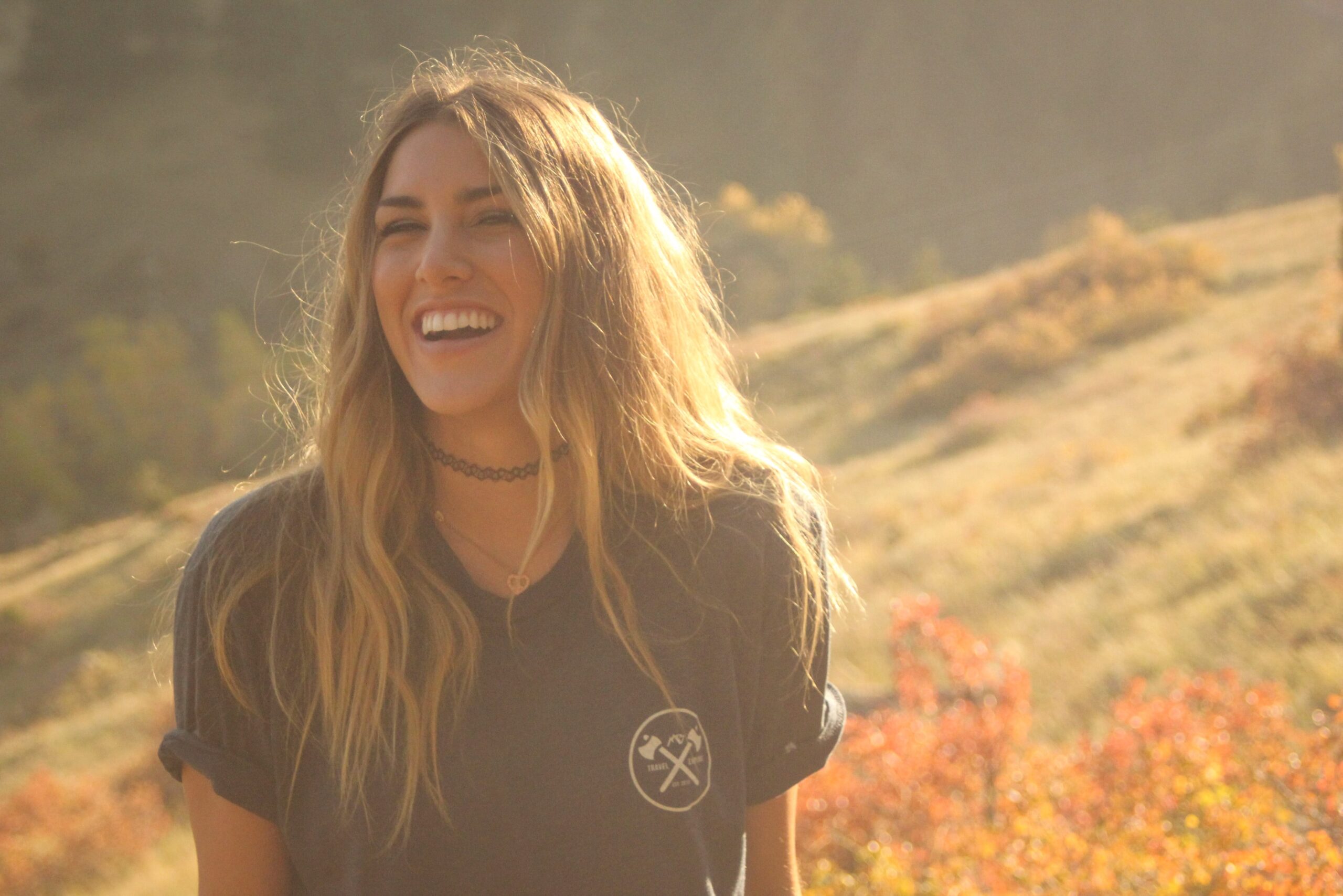 Joyful woman laughing outdoors in autumn sunlight